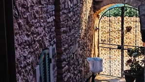 A stone building with a rustic exterior, a metal gate, and a view of a distant landscape. - Artist's Refuge (Cerri)