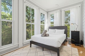 Een slaapkamer met een bed, een dressoir en een lamp.