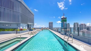 Une piscine sur le toit, avec une eau d’un bleu cristallin, entourée de bâtiments modernes et offrant une vue sur le panorama urbain.