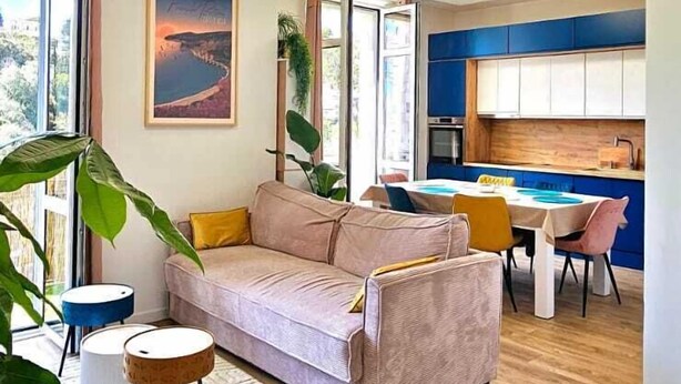 Een moderne woonkamer met een bank, een eettafel en een keuken op de achtergrond.