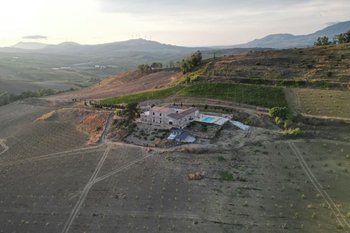 A large estate with a main building surrounded by fields and a swimming pool.