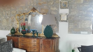 En byrå i trä med en spegel, en lampa och dekorativa föremål placerade framför en vägg av sten.