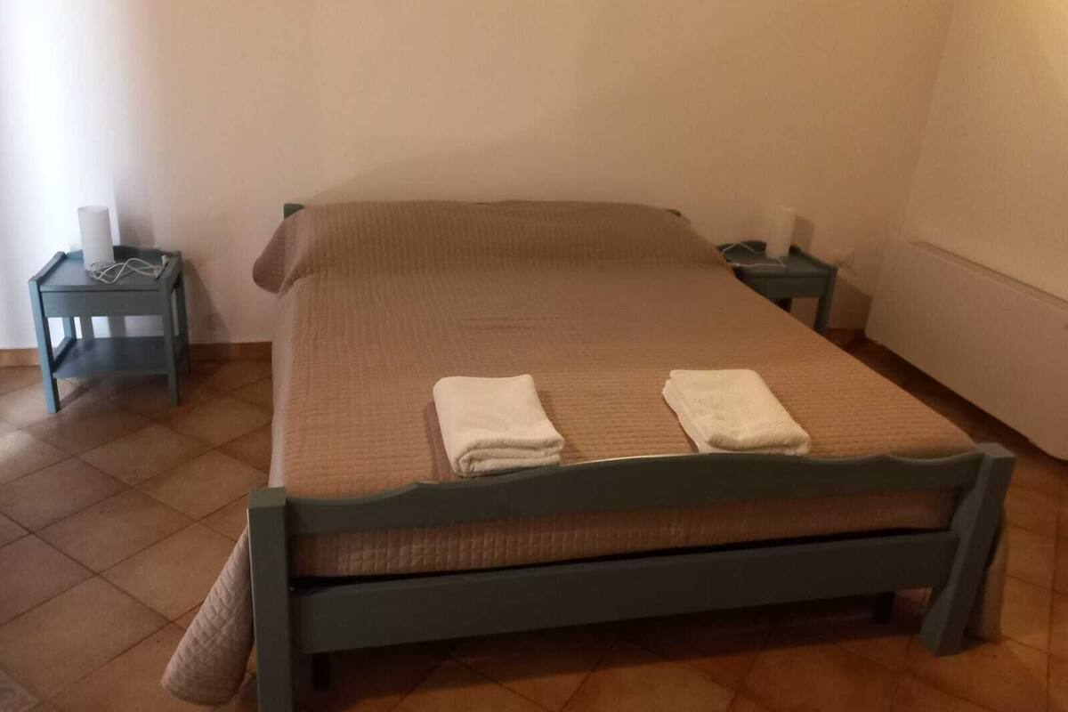 A single bed with a wooden frame and a brown quilted bedspread. There are two white towels folded on the bed.