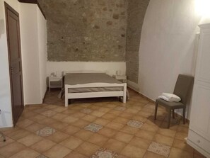Een slaapkamer met een bed, een stoel, een nachtkastje en een kledingkast.