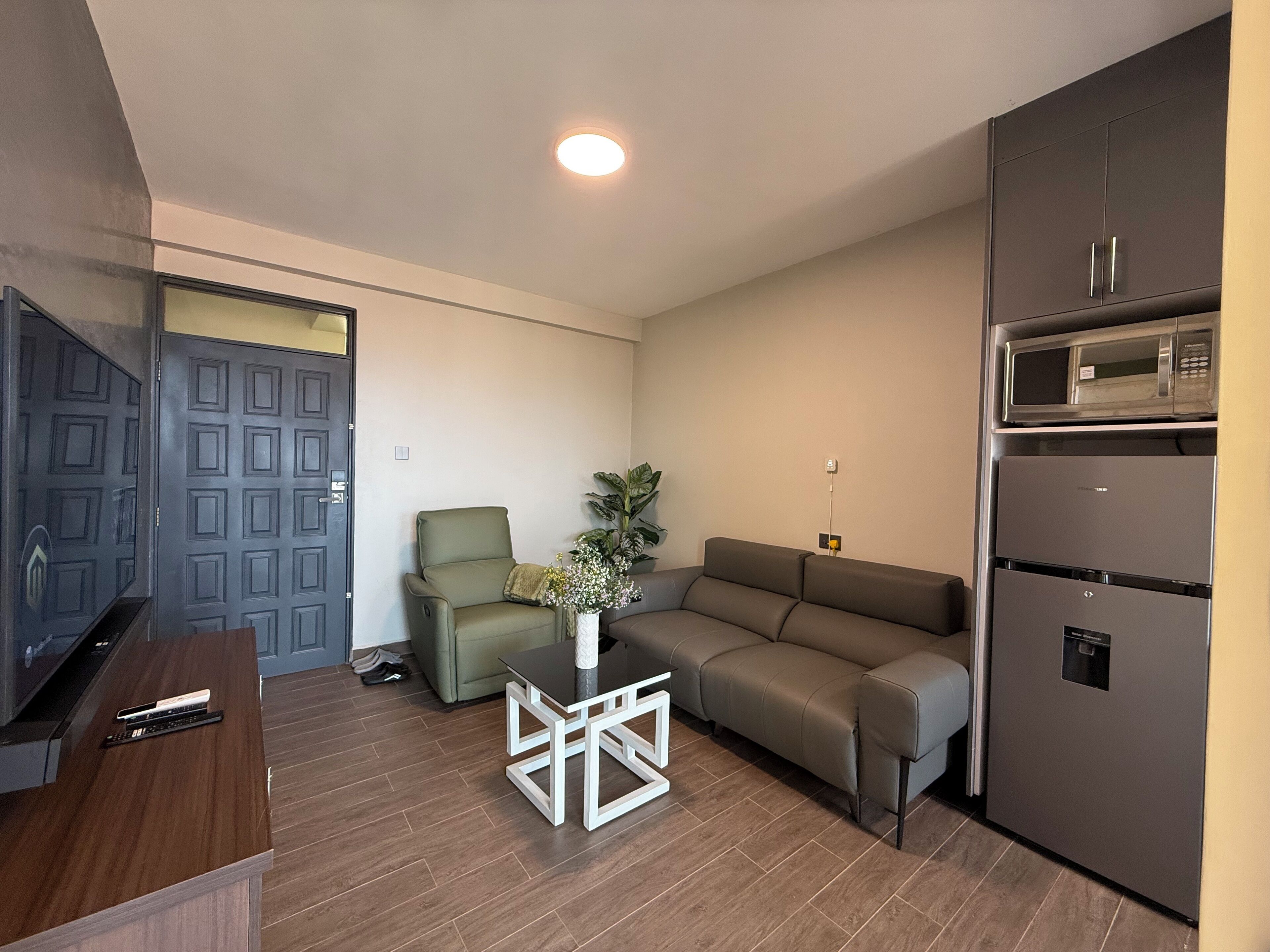 A compact living space with a sofa, a coffee table, a TV, and a built-in microwave.