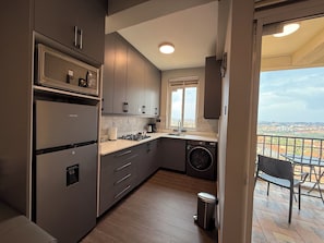 Uma cozinha moderna com máquina de lavar embutida, pia e janela com vista para a paisagem urbana.