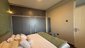 A bedroom with a bed, a wardrobe, a mirror, and a door.