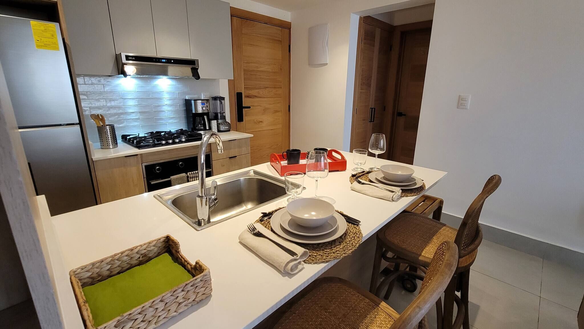 Una cocina moderna con una isla central, electrodomésticos de acero inoxidable y una zona de comedor preparada para dos.