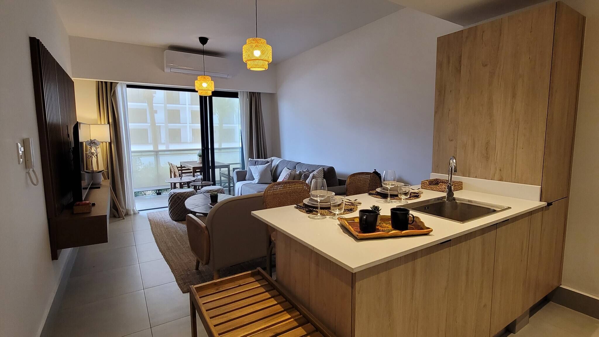 Cozinha moderna com ilha central, armários de madeira e área de jantar com sofá e cadeiras.