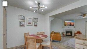 Ein Wohnzimmer mit Kamin, einem darüber montierten Fernseher und einem Essbereich mit rundem Tisch und Stühlen.