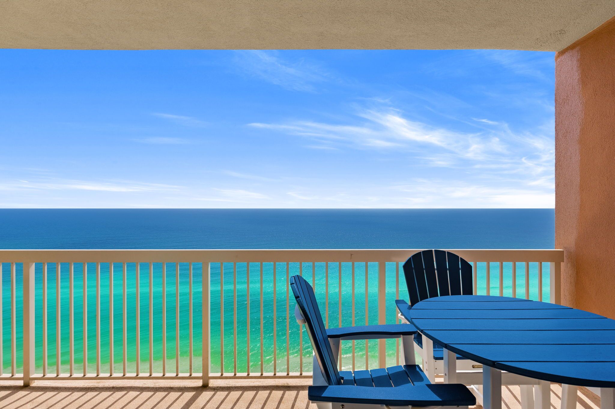 Varanda com vista para o oceano, uma mesa e duas cadeiras.