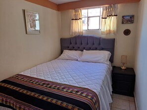 A neatly made bed with a quilted white duvet and a decorative black and colorful blanket. - Killainca House-Apartment furnished in Cusco city (Ciudad Del Cuzco, Cusco, Peru)
