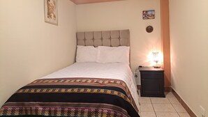 Une chambre  à coucher avec un lit, une table de chevet avec une lampe et un mur orné d’un tableau encadré.