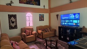 Un salon avec deux canapés, une table basse et un téléviseur posé sur un meuble.