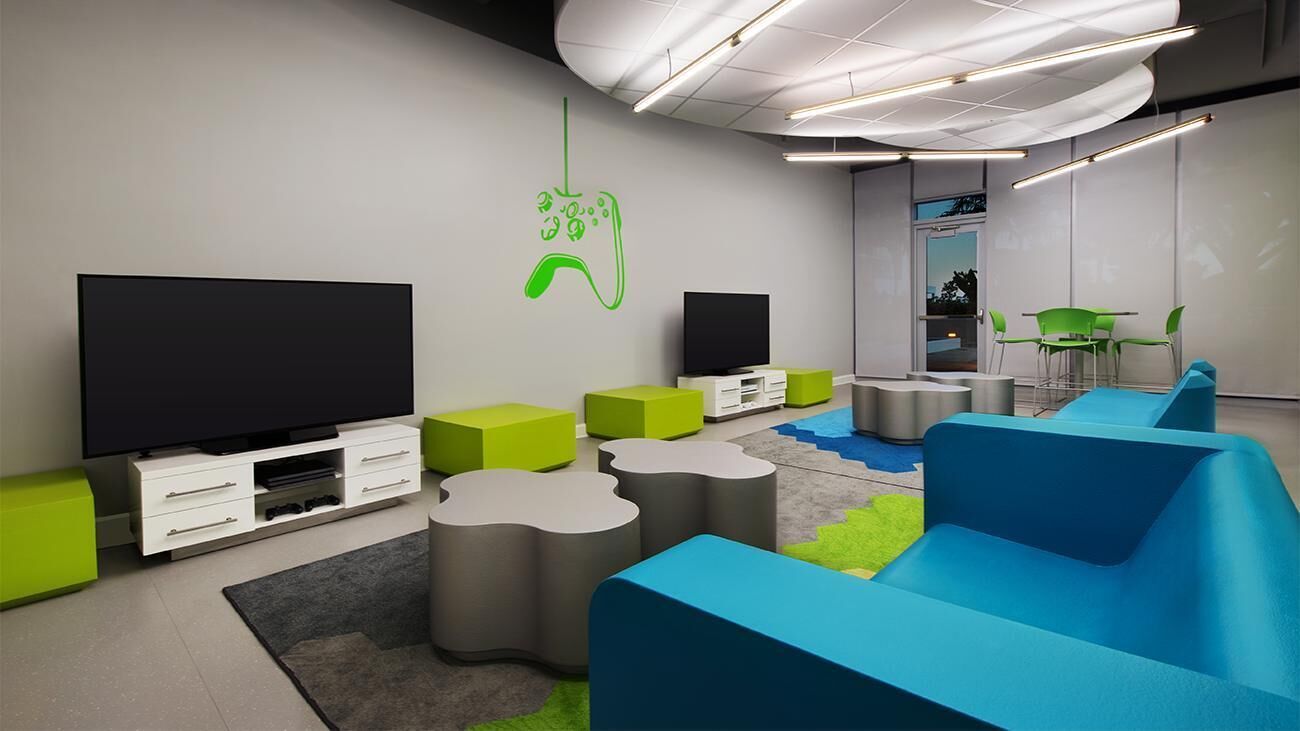 A modern lounge area with a flat-screen TV, green and blue seating, and a green wall decal.