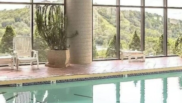 A pool area with a view of a hilly landscape, a potted plant, and a white chair. - Charming Ever Green 2-Bedroom Condo in Sugar Mountain with Resort Amenities (Sugar Mountain)