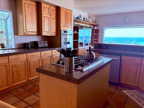 Una cocina con gabinetes de madera, encimera de granito, estufa, microondas y lavavajillas.