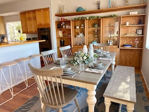 Un comedor con una mesa de madera dispuesta para cuatro personas, rodeada de sillas de madera.