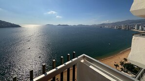 A coastal cityscape with a clear view of the sea, a beach, and distant mountains. - Spectacular View: Beachfront Apartment, La Palapa (Acapulco de Juárez)