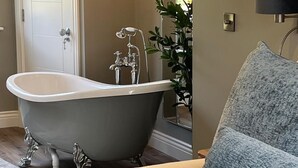 A bathroom with a clawfoot bathtub, a white door, and a plant.
