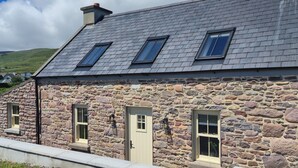 A stone building with a sloped roof, multiple windows, and a door.
