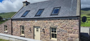 A stone building with a sloped roof, multiple windows, and a door.