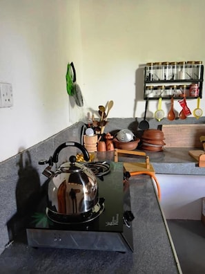 Una cocina con estufa a gas, hervidor y diferentes utensilios y utensilios de cocina.