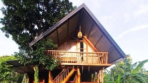 Una casa de madera con balcón, una escalera y un jardín con piedras para caminar.