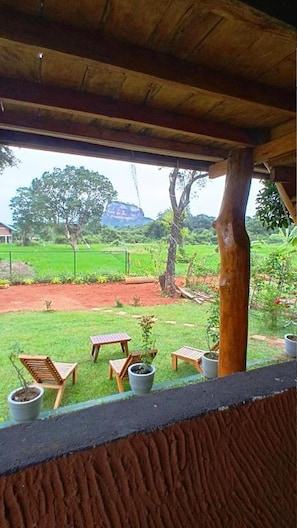Un espacio al aire libre techado con mobiliario de madera y plantas en macetas.
