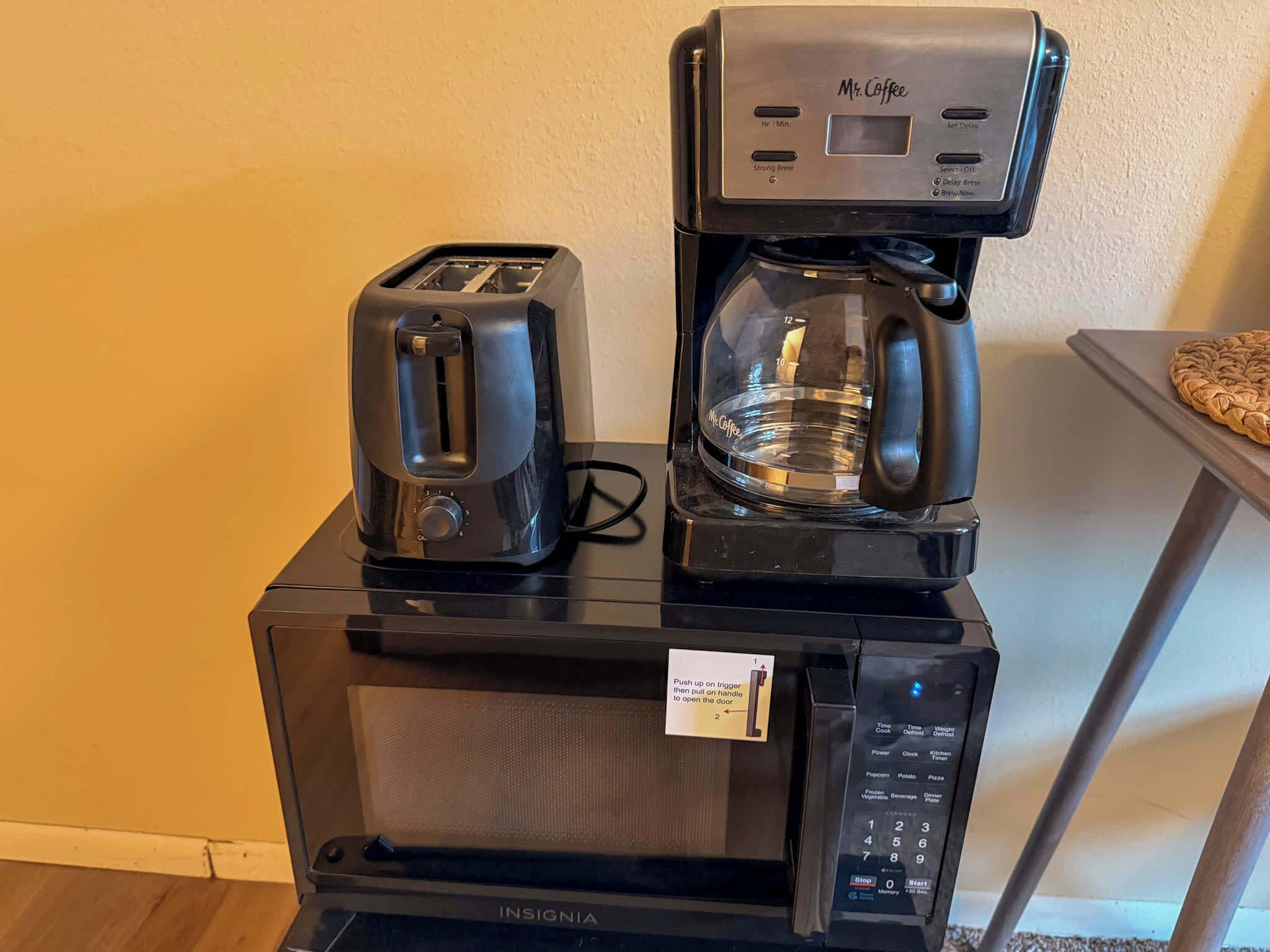 A Mr. Coffee maker on top of a microwave, with a toaster to the left.