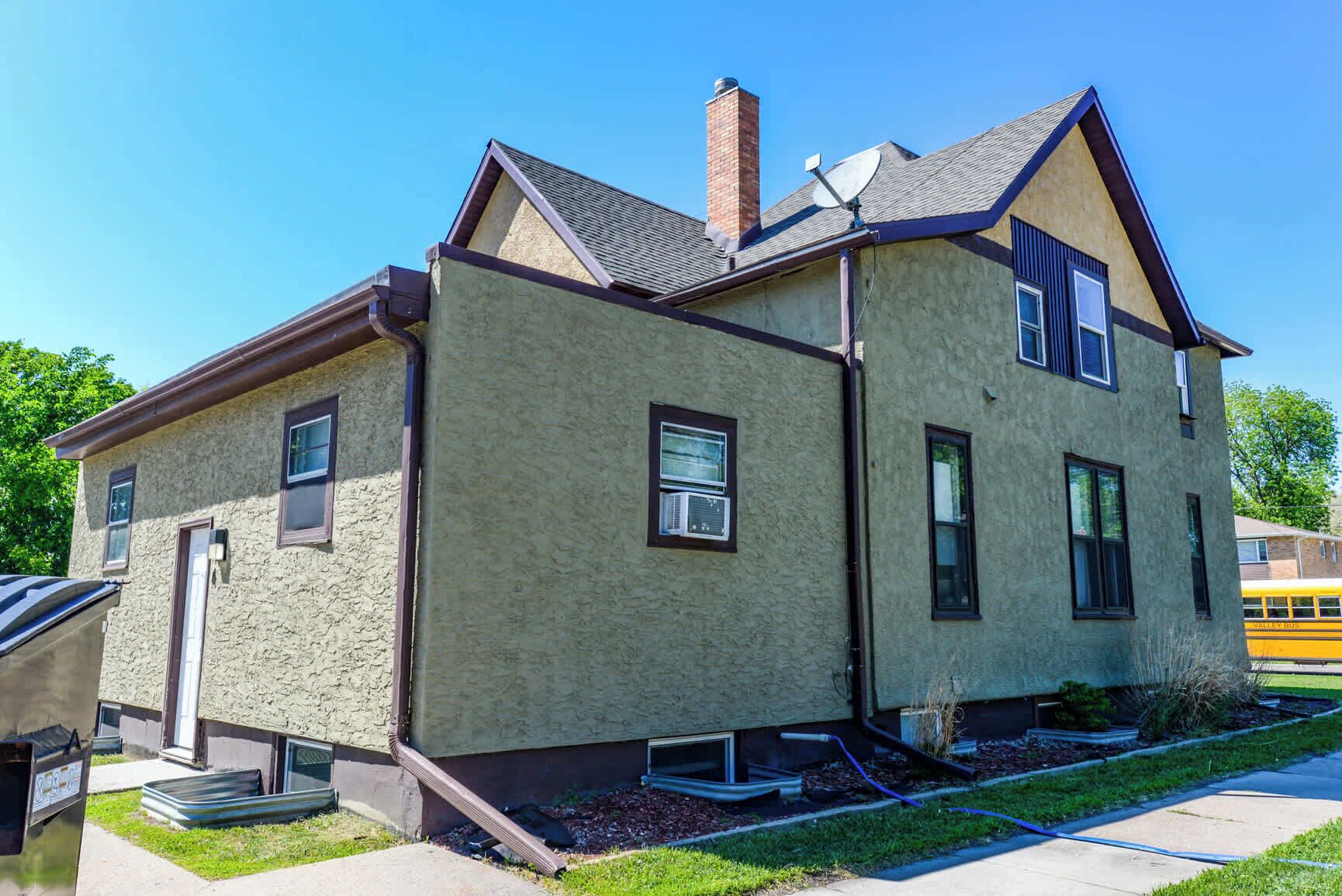 Une maison à deux étages avec une façade en pierre, une cheminée et une antenne parabolique.