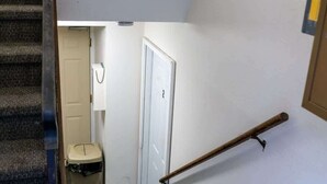 A staircase with a handrail, carpeted steps, and a door at the bottom leading to a room. - NDSU Efficiency (APT 3) (Fargo)