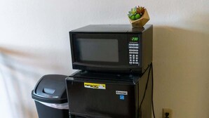 A black microwave and refrigerator stacked on top of each other with a small plant on the microwave. - Cozy Studio Near NDSU (Apt 5) (Fargo)