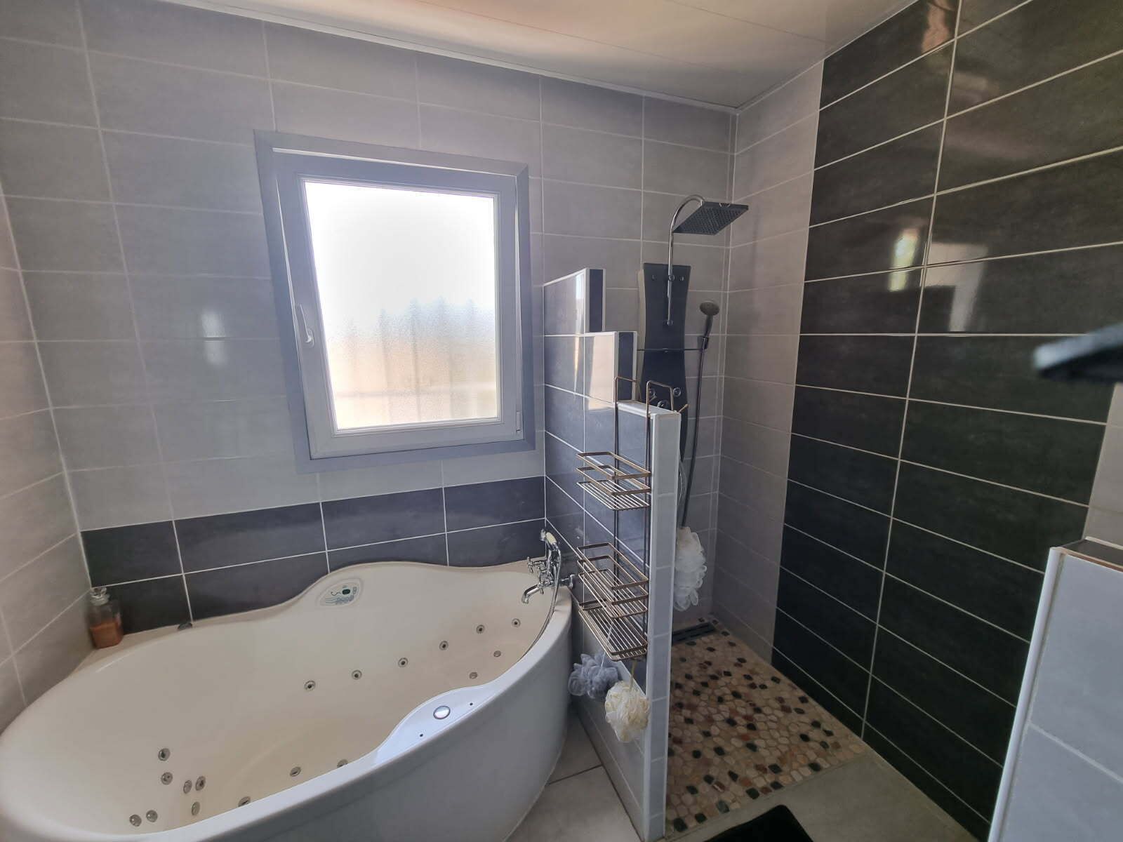 A bathroom with a bathtub, a shower, and a window.