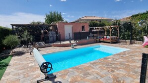 A swimming pool with a stone deck, a pergola, and a small garden area. - House Seasonal rental with swimming pool (Millau)