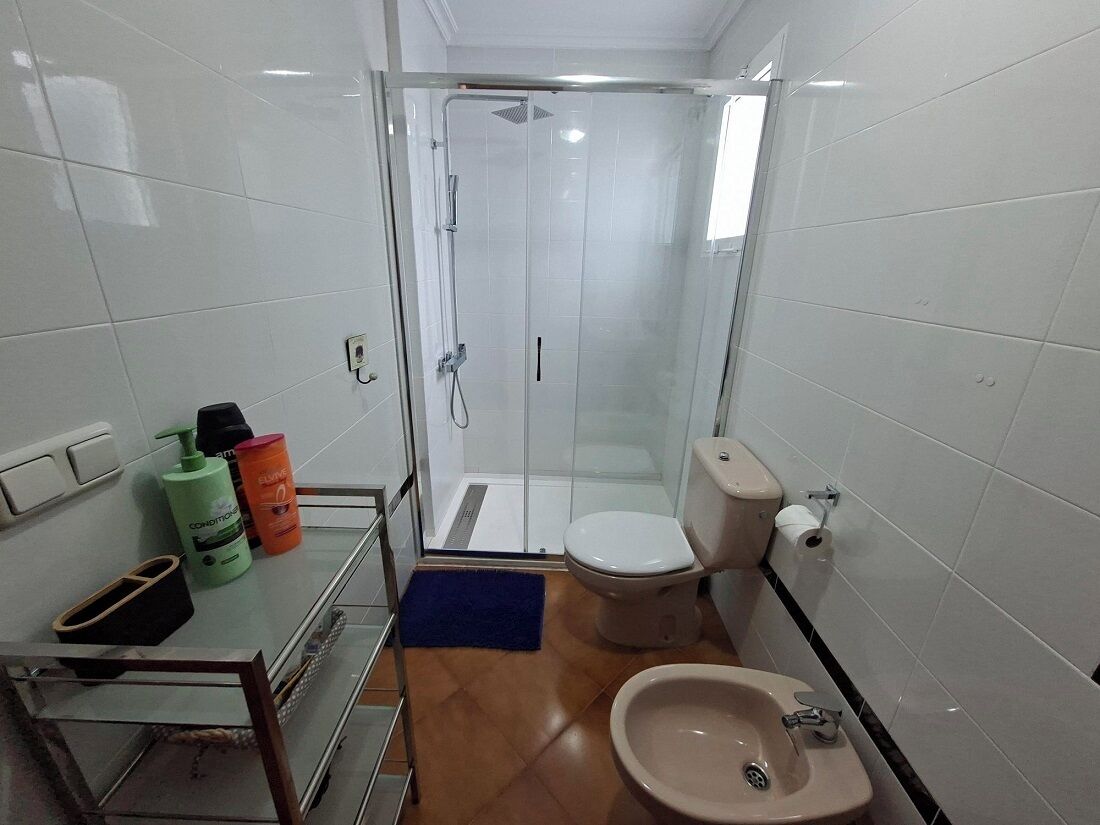A compact bathroom with a glass-enclosed shower, a toilet, and a sink.