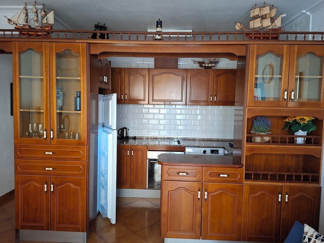 Eine Küche mit Holdekor-Schränken, einem Kühlschrank und einem Spülbecken.