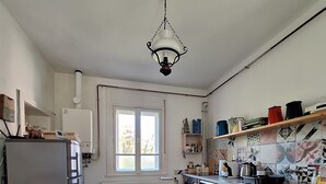 A compact kitchen with a built-in stove, a refrigerator, and a window. - Romantic vacation apartment with large garden - 2 min. from private natural swimming lake (Kerkateskánd)