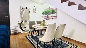 Uma área de refeições com uma mesa, cadeiras, um tapete e uma parede com a obra de arte 'GRACE'.