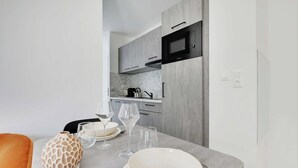 Una cucina moderna con mobili grigi, un forno a microonde e un'area pranzo con tavolo imbandito per due persone.
