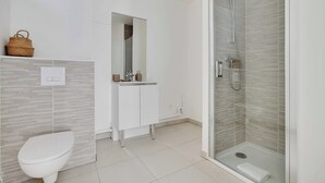 Un bagno moderno con un WC, un lavandino, uno specchio e una cabina doccia in vetro.