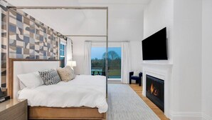 Ein Schlafzimmer mit einem großen Bett, einem an der Wand befestigten Fernseher und einem Kamin.