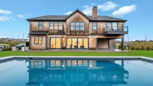 Ein zweistöckiges Haus mit Schwimmbecken davor.