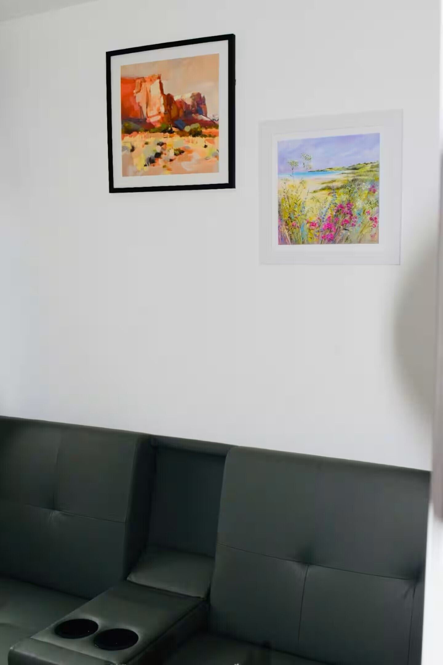 Une pièce avec un canapé vert foncé et deux tableaux encadrés accrochés au mur.