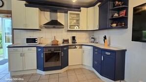 Une cuisine moderne avec des meubles blancs et bleu foncé, un four encastré, un four à micro-ondes et un lave-vaisselle.