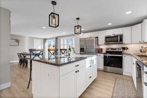 Una cocina moderna con armarios blancos, electrodomésticos de acero inoxidable y una isla central.