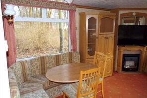 Ein gemütliches Wohnzimmer mit einem runden Holztisch, einer gepolsterten Bank, einem Holzschrank und einem Kamin.