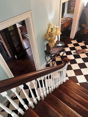 A staircase with a checkered floor, a wooden handrail, and a white balustrade.