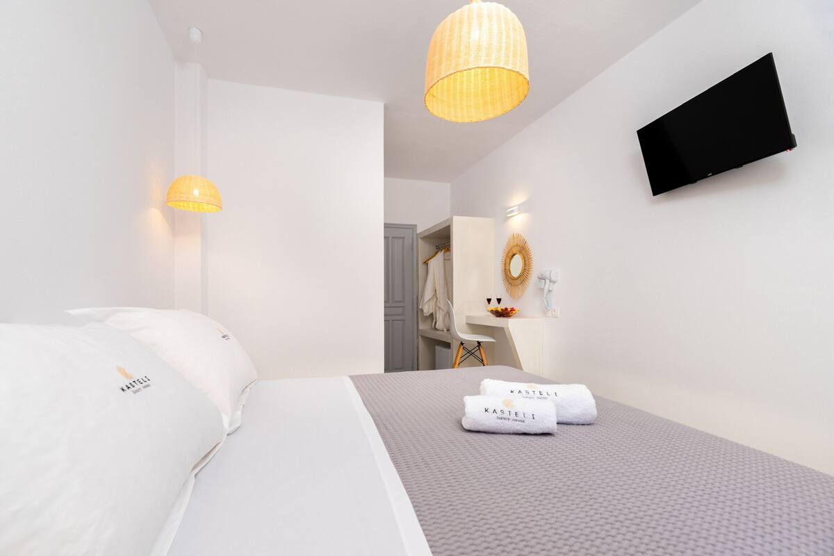 Een hotelkamer met een bed, een bureau, een televisie en een badkamer op de achtergrond.