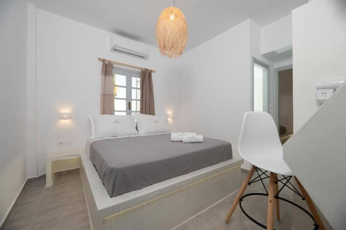 Een moderne slaapkamer met een bed, nachtkastjes, een stoel en een hanglamp.